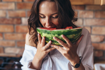 Woman at home eating watermelon in the kitchen