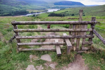 Fototapeta na wymiar five bar wooden fence with stile and dog on other side with countryside view