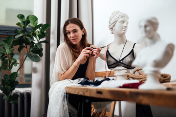 Female lingerie designer sits in her workshop