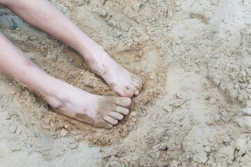 The boy's feet on the beach of a forest lake