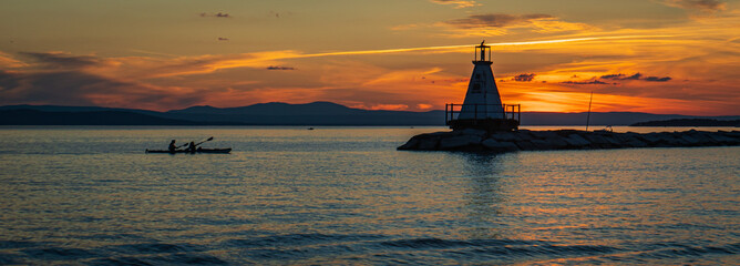 banner photo of kayakers approaching the Lake Champlain breakwater's lighthouse with a sea bird...