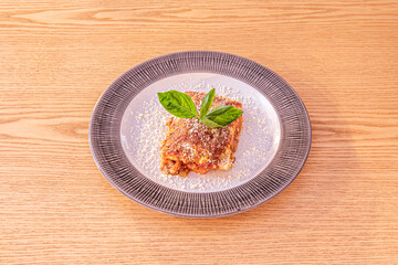 Lasagna portion stuffed with Italian recipe osso buco meat stew with grated cheese and basil