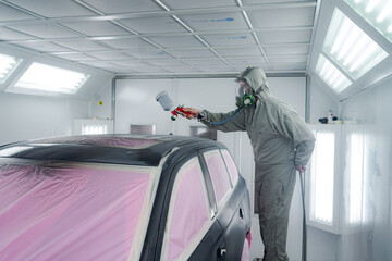 Man in workwear painting car in workshop