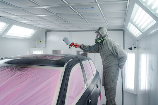 Man In Workwear Painting Car In Workshop