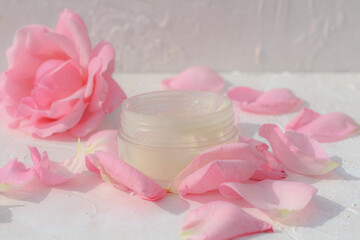 Obraz na płótnie Canvas Moisturizer jar decorated by tender rose flower and rose petals. Beauty blogger idea for post, natural cosmetics, romantic background