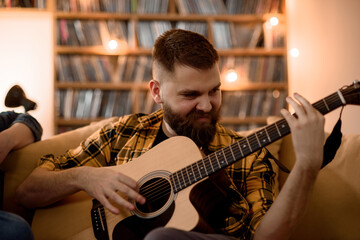 Young passionate man playing guitar while relaxing at home