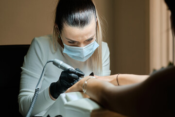 Manicurist polishing nails of client with apparatus