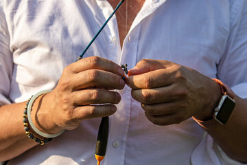 Male hands put bait on a fishing rod's hook. Fishing with a spinning rod