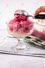 Strawberry frozen yogurt in glass bowl, ice cream balls, container with homemade sundae