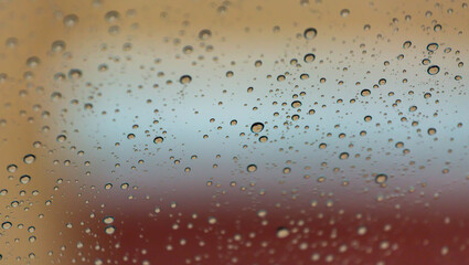 Rain drops on a windshield with a noticeable reflection in the droplets