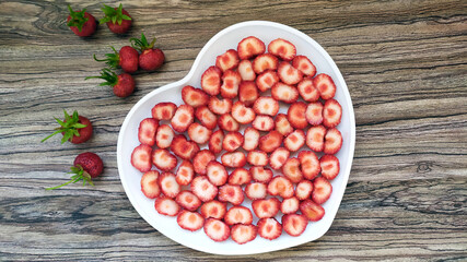 Strawberries in a white plate with a heart. A romantic serving of a healthy dessert. Red wholesome...