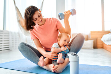 A sports mother is engaged with the child in fitness and yoga at home. The concept of sports, motherhood and an active lifestyle. Young woman in sports training with her child.