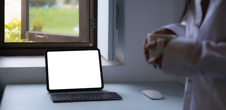 Mockup image of a black tablet with white blank screen on wooden desk.