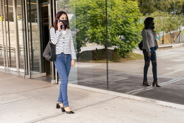 Horizontal portrait of a successful young female businesswoman talking business on her cell phone while walking. Telecommunications concept.