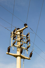 A concrete electric pole with steel cables in blue sky, vertical image