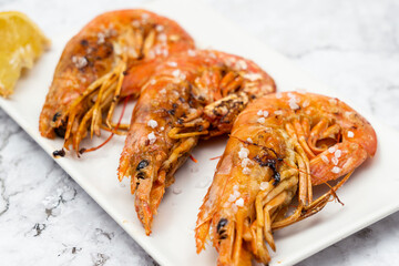 Gambones  a la plancha con limon  encima de una mesa 