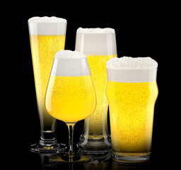Set of fresh light beer glasses with bubble froth isolated on black background.