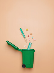 Medical trash falling in trash container on orange pastel background