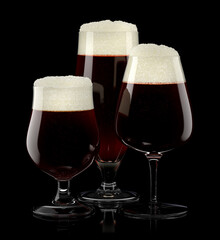 Set of fresh draft beer glasses with bubble froth isolated on black background.