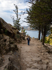 Fototapeta premium Person walking in a religious hike trail in nature in moon lagoon in lake titicaca peru and bolivia