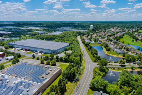 Panoramic aerial view on solar panels on absorb sunlight sustainable energy of building warehouse roof near small American town