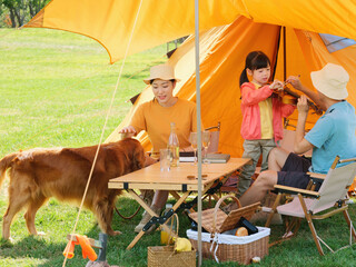 Happy family of three and pet dog playing violin outdoors