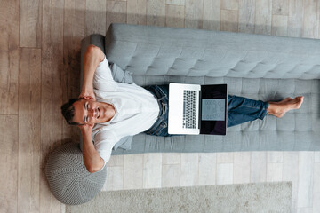 happy man with a laptop resting on the couch .