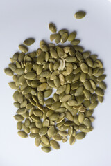 Top view of a pile of peeled pumpkin seeds on white background.