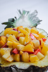 Pineapple dessert stuffed with a variety of tropical fruits close up.
