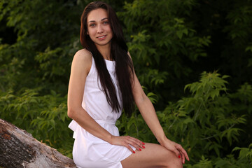 Beautiful woman in white dress sitting on a snag in the lake