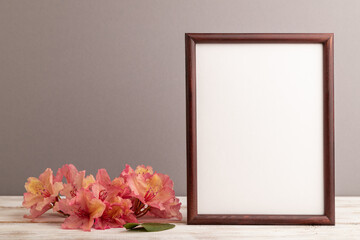 Wooden frame with pink azalea flowers on gray pastel background. side view, copy space.