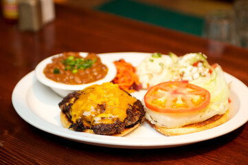 Open faced cheese burger with cheddar cheese, lettuce, and tomato.