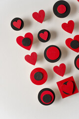 hand painted red hearts and black discs and squares arranged on a white background in low-key ambient light