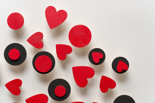 hand painted red hearts and black discs loosely arranged on a light background - photographed from above in ambient light - prominent shadows or three dimensionality