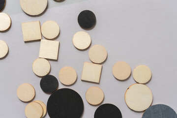 wooden shapes (squares and circles) - some painted black - on a warm gray background