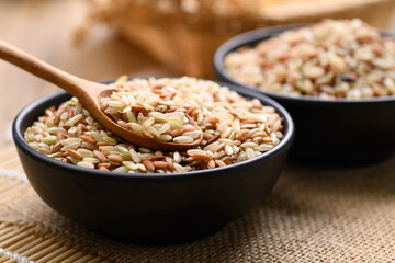 Organic Thai highland brown rice grain in a spoon and bowl (Cargo rice, Loonzain rice or Husked rice), Healthy food