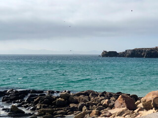 IMAGEN DE LA COSTA DE TARIFA, CON EL MAR AZUL, PAJAROS VOLANDO Y MARRUECOS AL FONDO, EN UN DIA...
