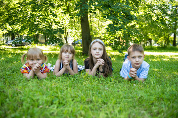 Fototapeta premium Children lie on a green meadow with their hands under their chin on a summer day