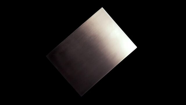 Isolated metal plate with abstract texture rotating on a black background. Abstract reflection on copper plate