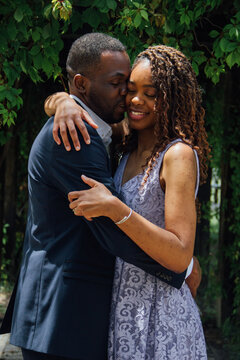 Pareja de novios africanos enamorados se dan besos y abrazos en un parque 