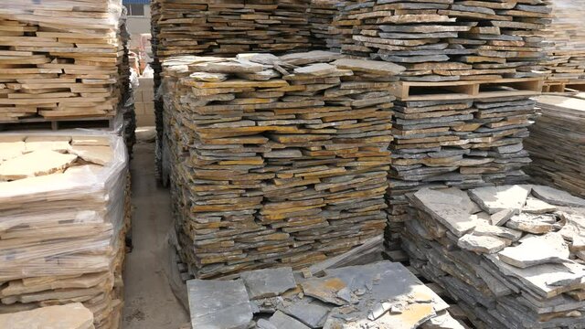  Natural stone blocks packed in stacks are stored on ground outdoors at a hardware store warehouse