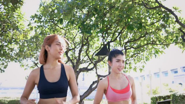 Happy Asian female friends in sportswear running and jogging in outdoor park for a fit and healthy lifestyle