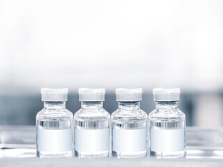 Medical vaccine vials with white blank label on tray with copy space. Close up image of four vaccine glass bottles for injection.