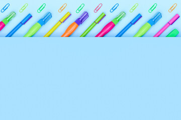 Multicolor bright school and office stationery items in a row on a blue background with copy space. Proofreaders, pens and paper clips. Flat Lay.