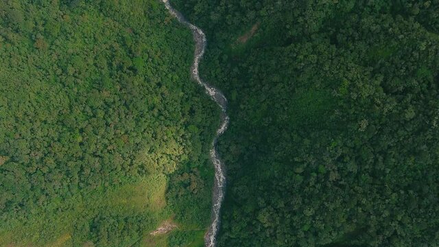 Cinematic cenital view of the river, surrounding by the jungle road to the lost city in Peru