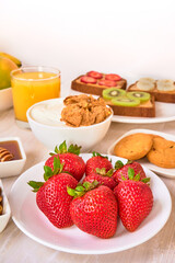 fresh strawberries on a white plate ready to eat with honey, yogurt and walnuts on a marble surface and a white background. healthy low calorie breakfast. copy space for advertising.