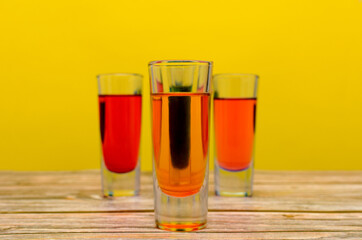 Bebidas coloridas sobre mesa de madera con fondo amarillo