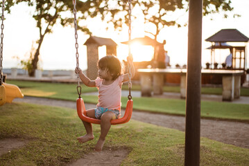 Asian baby girl playing on a swing and having fun in park