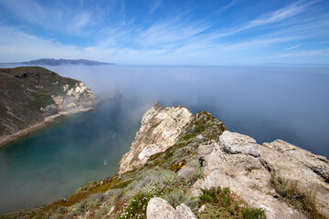 Cloud mist over Potato Harbor on Santa Cruz Island with mist coming in under blue cirrus sky in the Channel Islands National Park offshore from Santa Barbara California USA