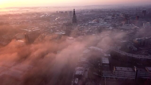 Drone shot of the skyline of Breda on a warm and cloudy morning with the Grote Kerk church in the middle.